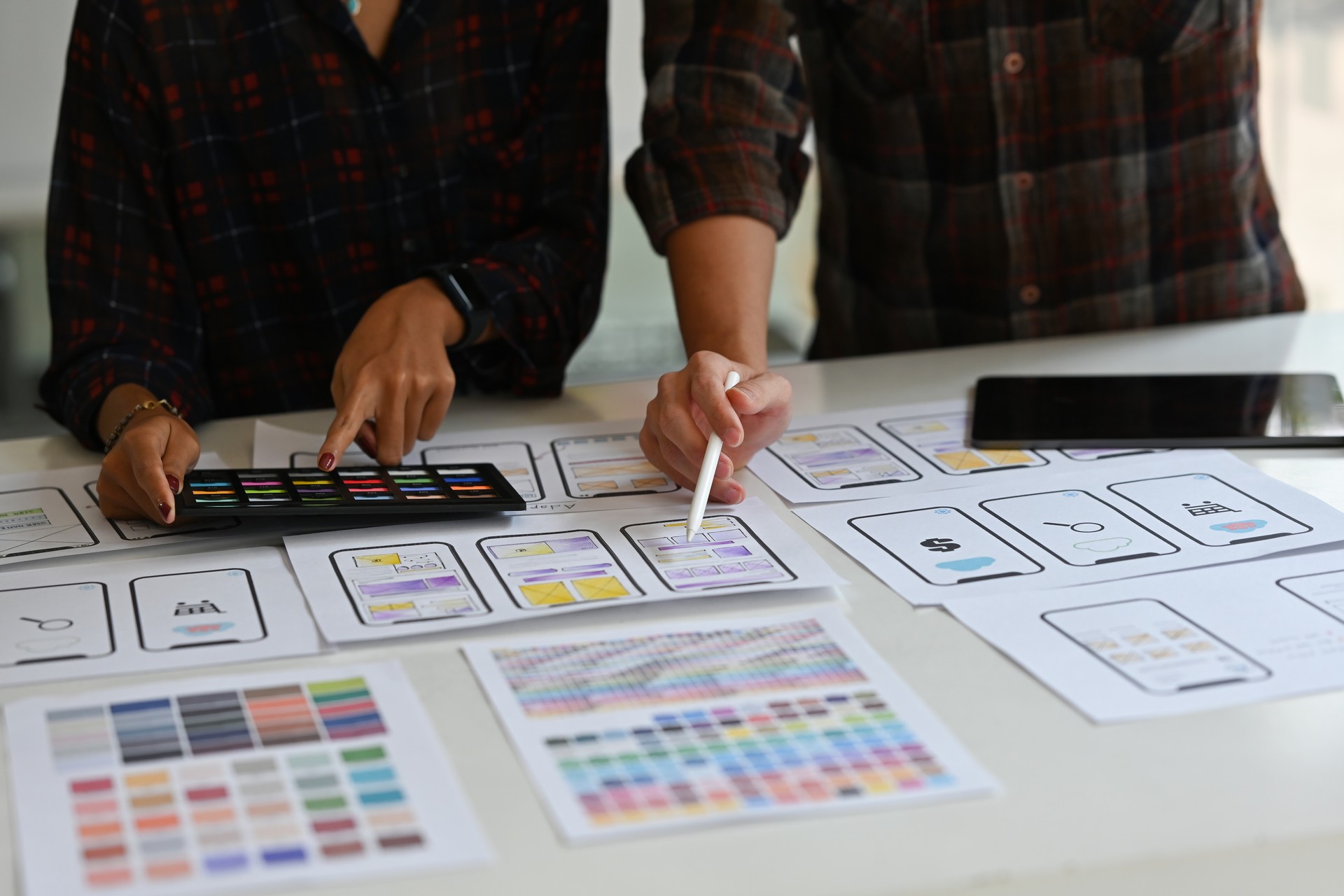 Close up Creative Ux developer and Ui designer brainstorming about mobile app interface wireframe design on table with customer brief and color code.